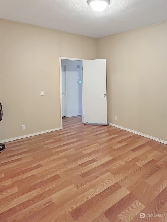 empty room with a textured ceiling and light hardwood / wood-style flooring