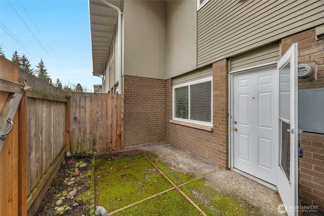 property entrance featuring brick siding and fence