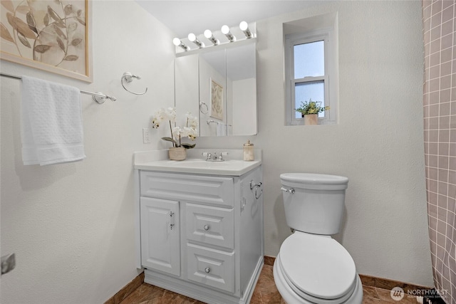 bathroom with vanity, toilet, and baseboards