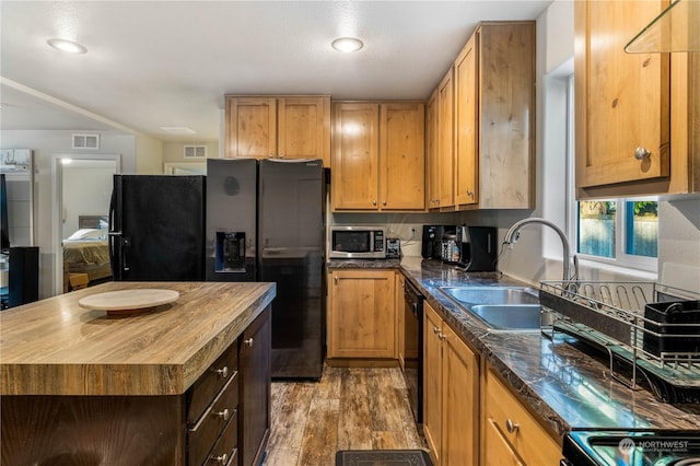 kitchen featuring sink, light hardwood / wood-style flooring, wooden counters, black dishwasher, and a kitchen island