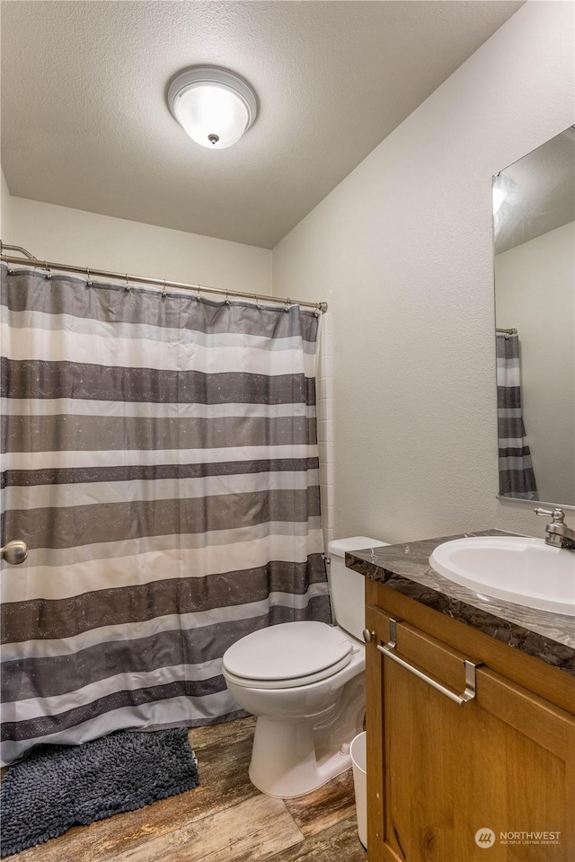 bathroom featuring vanity, toilet, wood-type flooring, and a textured ceiling