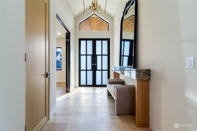 interior space featuring vaulted ceiling, a chandelier, light hardwood / wood-style floors, and french doors