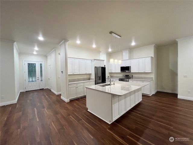 kitchen featuring decorative light fixtures, stainless steel appliances, an island with sink, and white cabinets