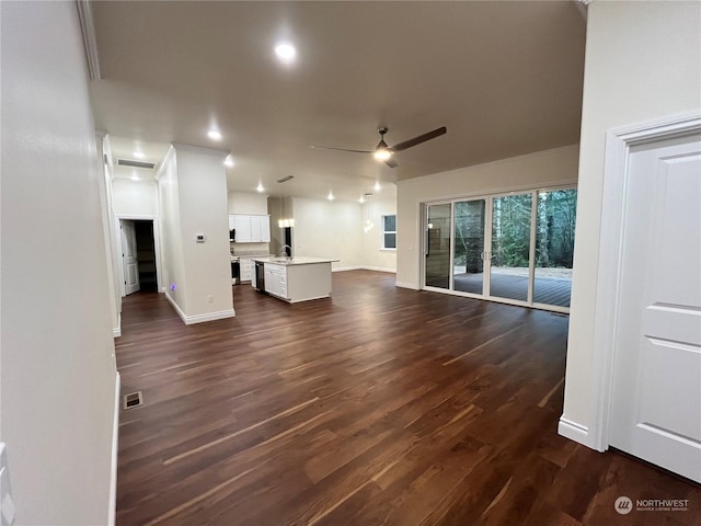 unfurnished living room with sink, dark hardwood / wood-style floors, and ceiling fan