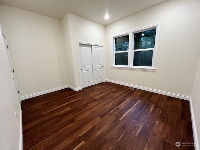 unfurnished bedroom with dark wood-type flooring and a closet