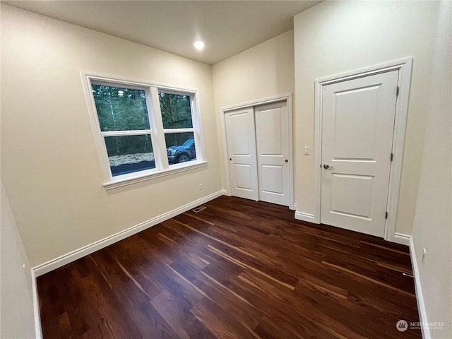 unfurnished bedroom featuring dark hardwood / wood-style flooring and a closet