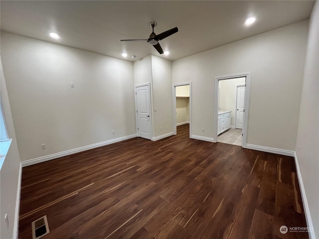 unfurnished bedroom with connected bathroom, a spacious closet, dark hardwood / wood-style floors, a closet, and ceiling fan