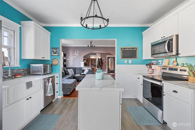 kitchen featuring decorative light fixtures, white cabinets, a center island, a notable chandelier, and stainless steel appliances