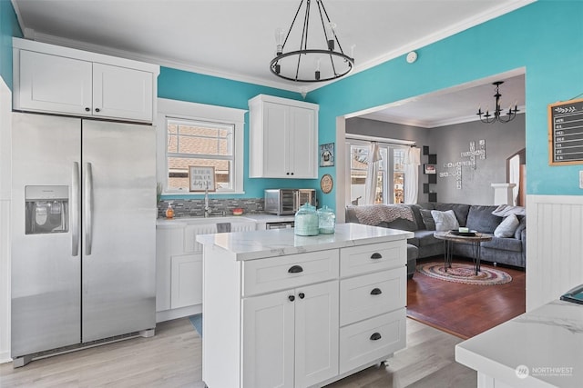 kitchen with white cabinetry, stainless steel fridge with ice dispenser, decorative light fixtures, and an inviting chandelier