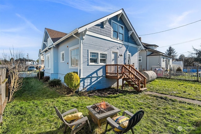 back of house featuring a lawn and an outdoor fire pit