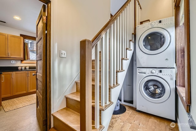 washroom with stacked washer and dryer and light wood-type flooring