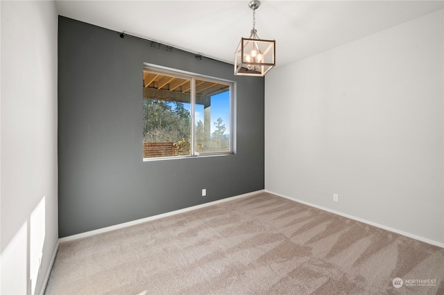 carpeted spare room with a chandelier