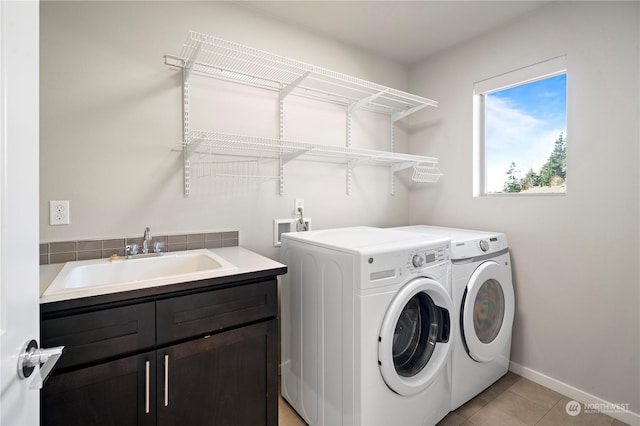 clothes washing area with sink, cabinets, washer and dryer, and light tile patterned floors