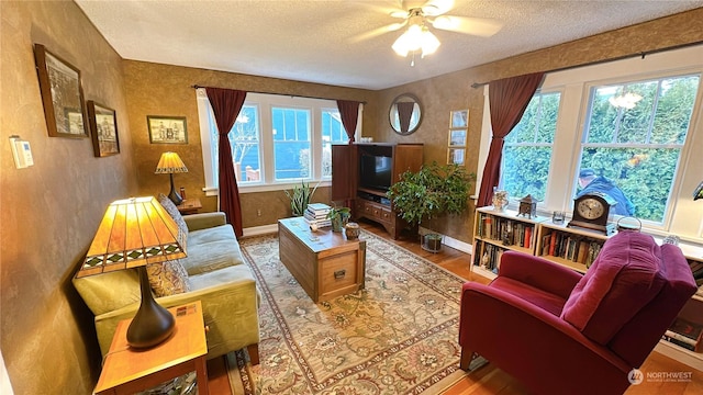 living room with ceiling fan, hardwood / wood-style floors, and a textured ceiling