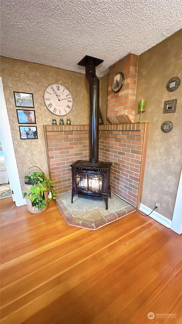 room details featuring hardwood / wood-style flooring, a wood stove, and a textured ceiling