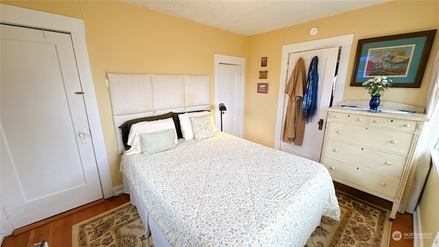 bedroom with wood-type flooring, a closet, and a textured ceiling