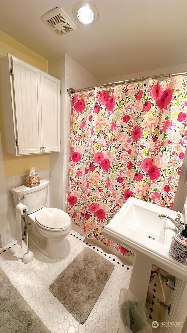 bathroom with a shower with shower curtain and toilet