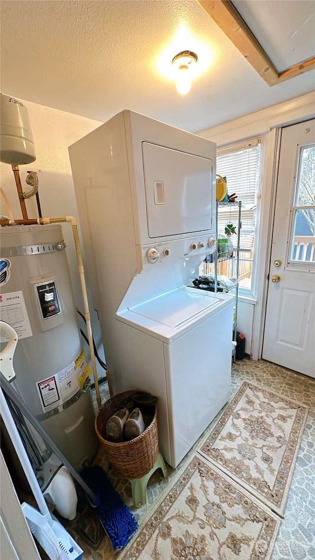 laundry room with strapped water heater, a textured ceiling, and stacked washing maching and dryer