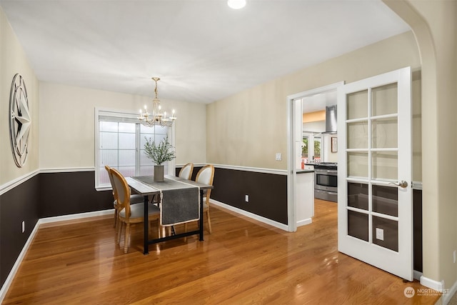 dining room featuring a notable chandelier, baseboards, arched walkways, and wood finished floors