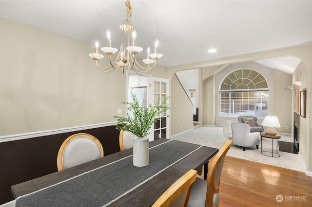 dining space with lofted ceiling, a notable chandelier, light wood-style flooring, and baseboards