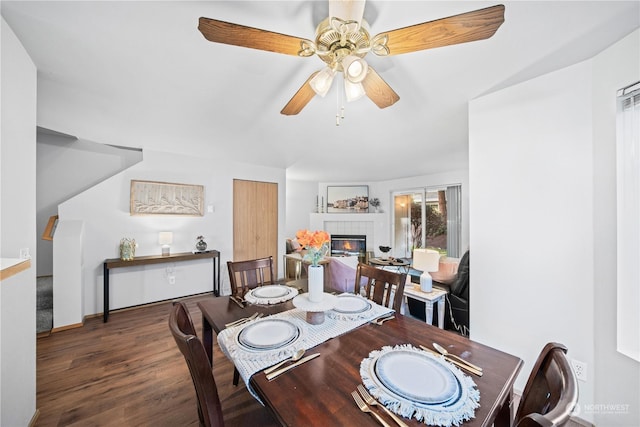 dining room with a tiled fireplace, dark hardwood / wood-style floors, and ceiling fan