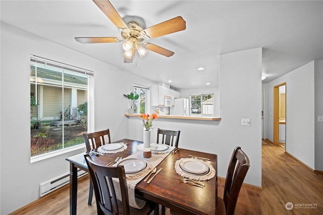 dining space with a baseboard heating unit, hardwood / wood-style flooring, and ceiling fan