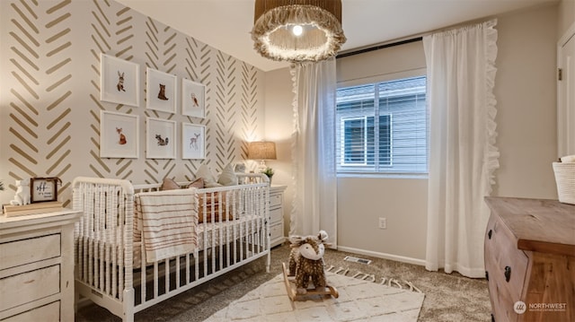 carpeted bedroom with a crib and an inviting chandelier