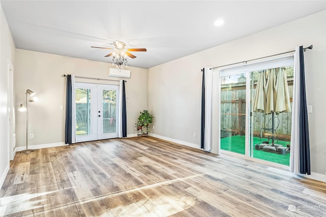 spare room with an AC wall unit, light hardwood / wood-style flooring, ceiling fan, and french doors