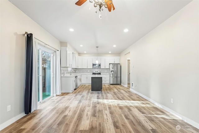 kitchen featuring white cabinetry, stainless steel appliances, light hardwood / wood-style floors, decorative backsplash, and decorative light fixtures