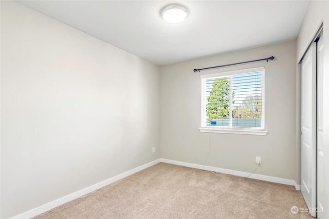 unfurnished bedroom featuring light colored carpet and a closet