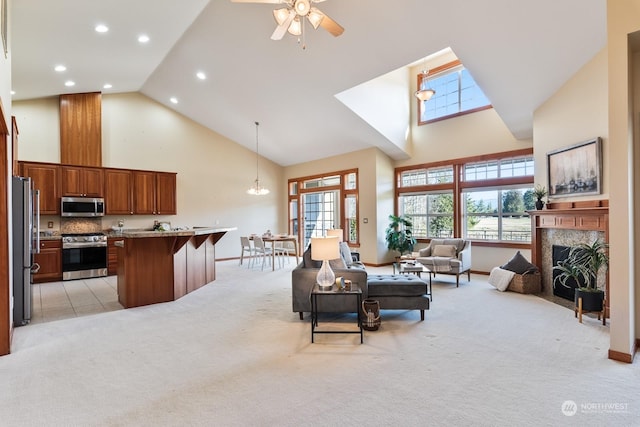 carpeted living room featuring ceiling fan with notable chandelier, a premium fireplace, and high vaulted ceiling