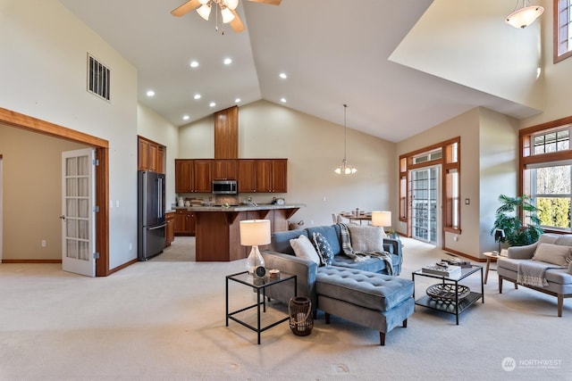 living room featuring ceiling fan with notable chandelier, light colored carpet, and high vaulted ceiling