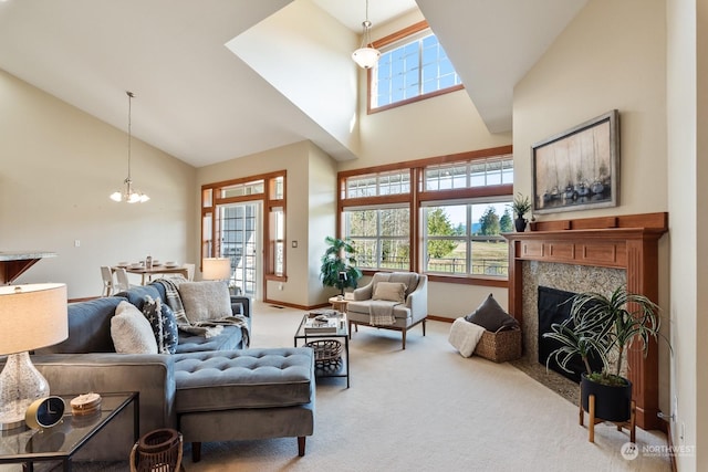 carpeted living room with a premium fireplace, high vaulted ceiling, and a notable chandelier