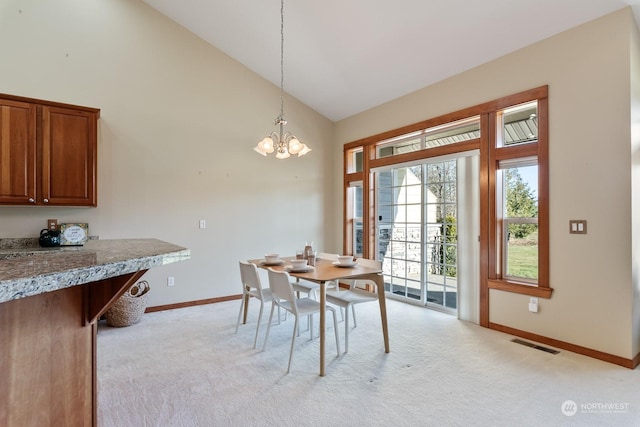 dining room with light carpet, a notable chandelier, and high vaulted ceiling