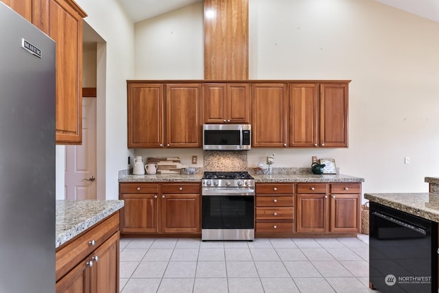 kitchen with light stone counters, light tile patterned floors, high vaulted ceiling, and appliances with stainless steel finishes