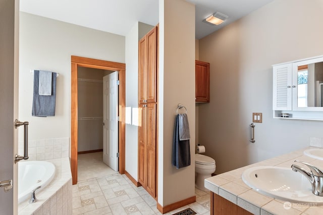 bathroom with vanity, toilet, and tiled bath