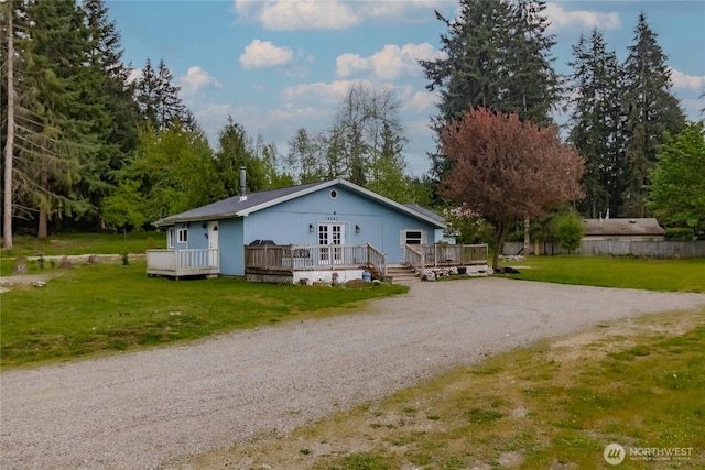 rear view of property featuring a deck, a yard, and dirt driveway