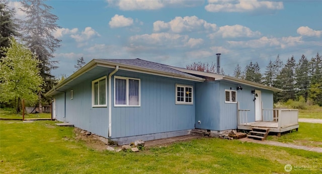 back of property featuring a deck and a lawn