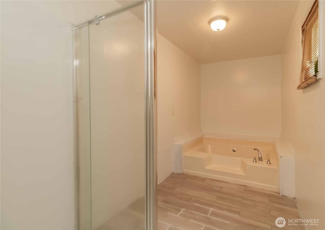 full bathroom with a stall shower, a bath, and wood finished floors