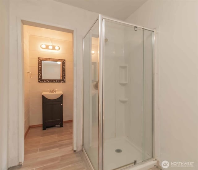 bathroom featuring wood finished floors, a stall shower, and vanity