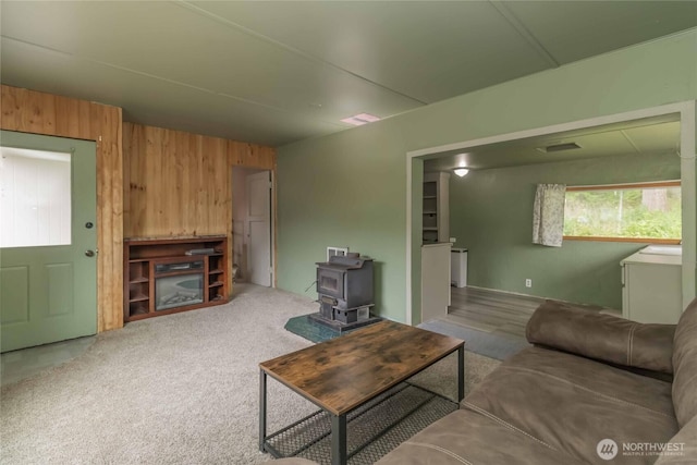 living room featuring wooden walls and a wood stove