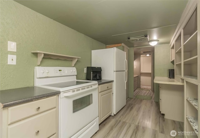 kitchen featuring white appliances, a textured wall, light wood-style floors, dark countertops, and cream cabinets
