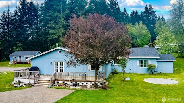 view of front of house featuring a wooden deck, a front lawn, french doors, and a shingled roof