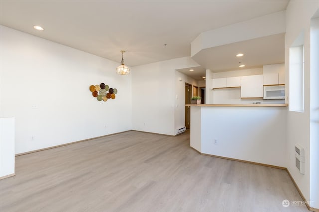 unfurnished living room featuring baseboard heating and light wood-type flooring