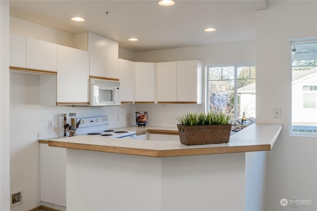 kitchen with white cabinetry, white appliances, and kitchen peninsula