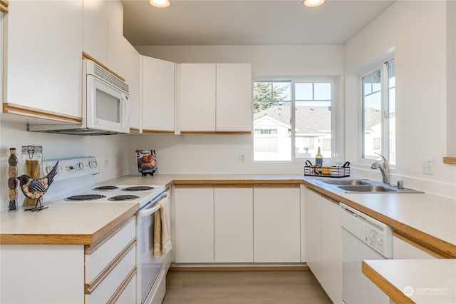 kitchen with sink, white appliances, light hardwood / wood-style flooring, and white cabinets