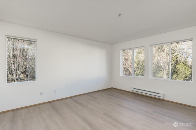 empty room with light wood-type flooring and a baseboard heating unit