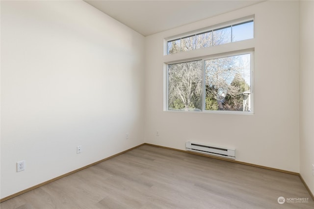 empty room featuring a baseboard heating unit and light wood-type flooring