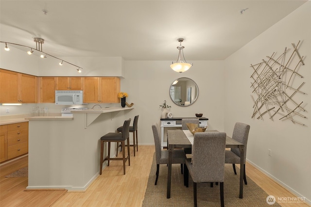 dining space with light wood-type flooring and track lighting