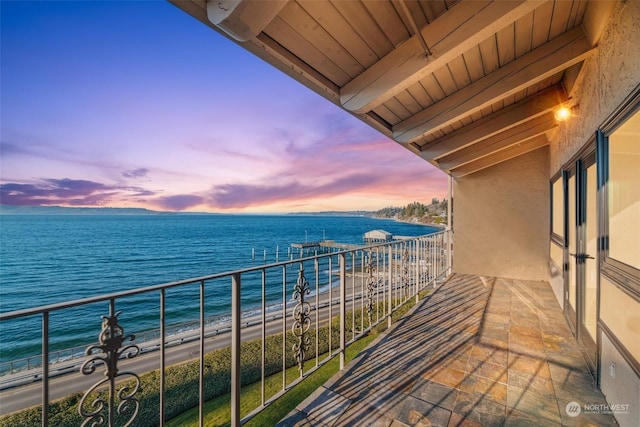 balcony at dusk with a view of the beach and a water view